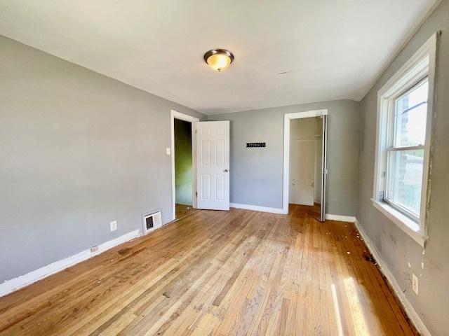 unfurnished bedroom featuring light wood finished floors, a closet, and baseboards