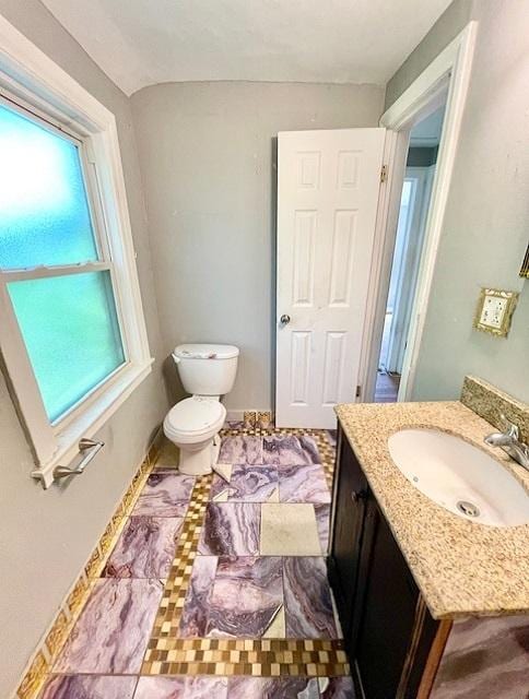 half bath featuring toilet, vanity, and baseboards