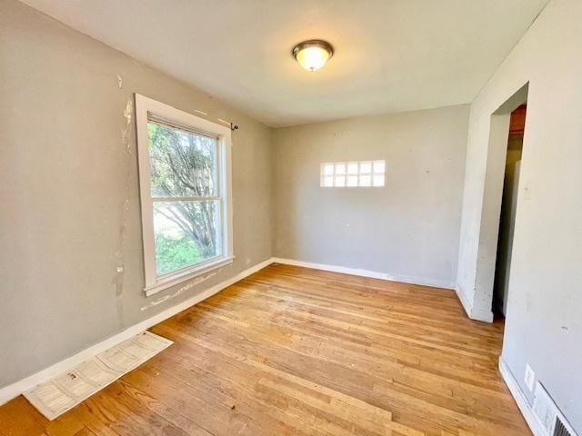unfurnished room featuring plenty of natural light, light wood-style flooring, and baseboards