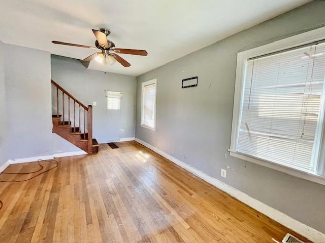 foyer entrance with baseboards, stairs, wood finished floors, and ceiling fan
