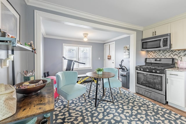 kitchen with appliances with stainless steel finishes, tasteful backsplash, crown molding, light wood finished floors, and light stone countertops