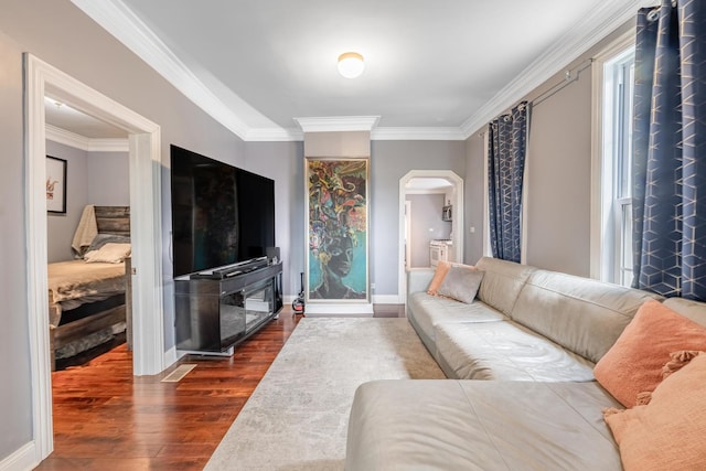 living area with dark wood-style floors, ornamental molding, baseboards, and arched walkways