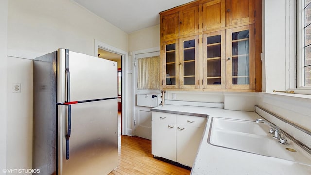 1366 E 57th St Unit 3, Chicago, IL 60637 - kitchen featuring freestanding refrigerator, a sink, light countertops, glass insert cabinets, and light wood finished floors