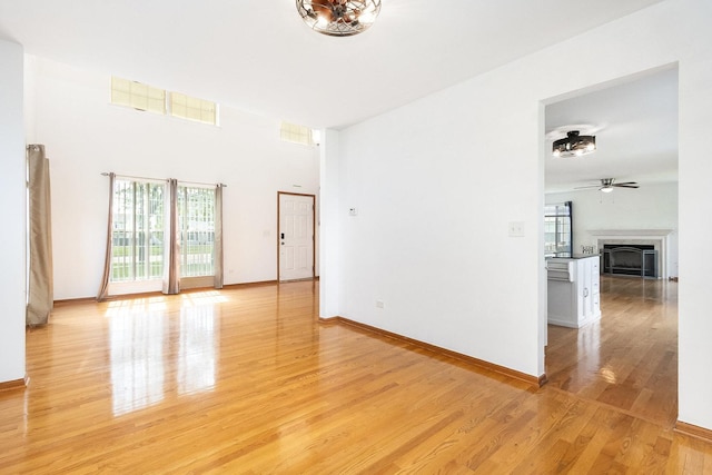 1376 Dahlgren Ln, Minooka, IL 60447 - unfurnished room featuring a fireplace, light wood-style floors, ceiling fan, and baseboards