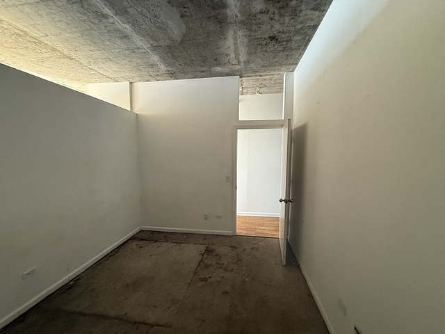 empty room with baseboards and unfinished concrete floors