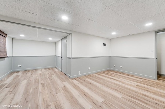 finished below grade area with wood finished floors, a drop ceiling, baseboards, and recessed lighting