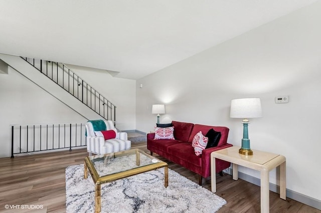 living area featuring wood finished floors, baseboards, and stairway