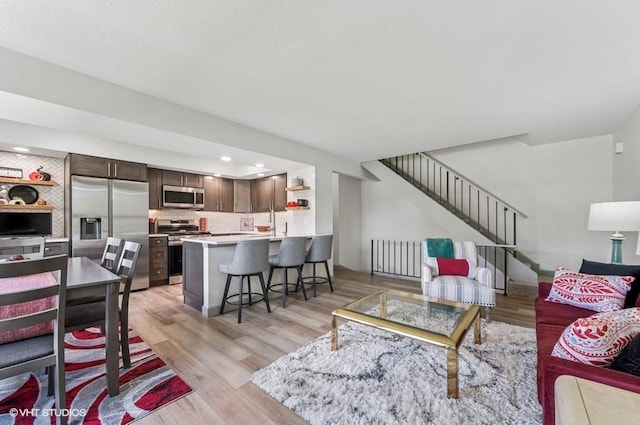 living area with light wood-style flooring, stairs, and recessed lighting