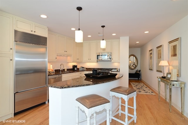 60 E Monroe St Unit 2607, Chicago, IL 60603 - kitchen featuring stainless steel appliances, light wood-type flooring, dark stone counters, recessed lighting, and decorative light fixtures