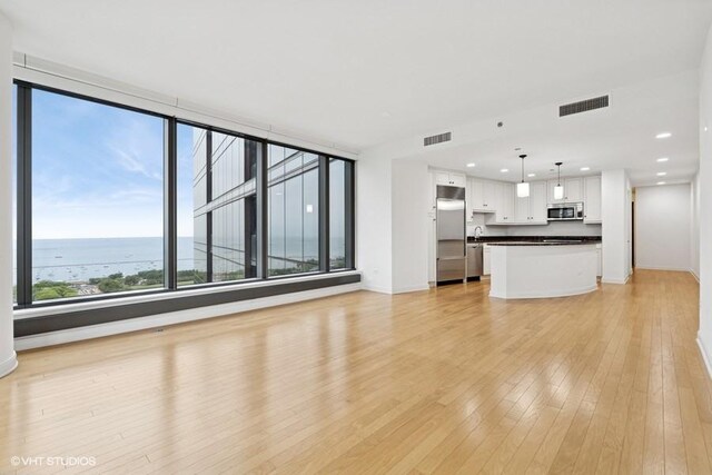60 E Monroe St Unit 2607, Chicago, IL 60603 - unfurnished living room featuring light wood-style flooring, baseboards, recessed lighting, a sink, and a water view