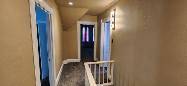 corridor featuring carpet flooring, vaulted ceiling, and baseboards