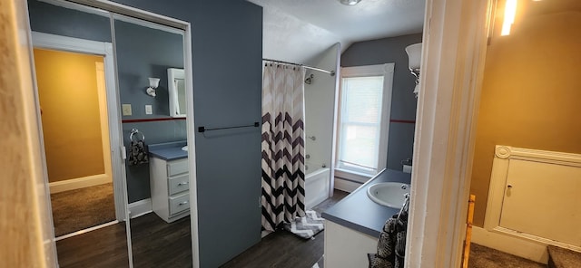 bathroom featuring vanity, wood finished floors, vaulted ceiling, shower / bath combo with shower curtain, and baseboards