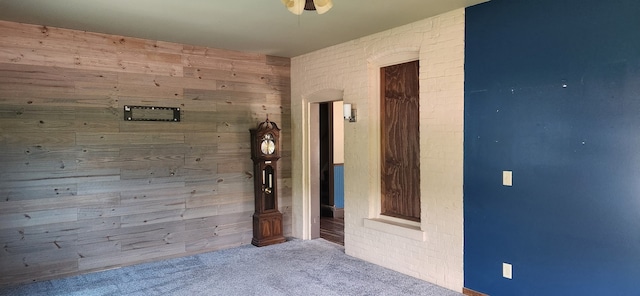 spare room featuring carpet and wood walls