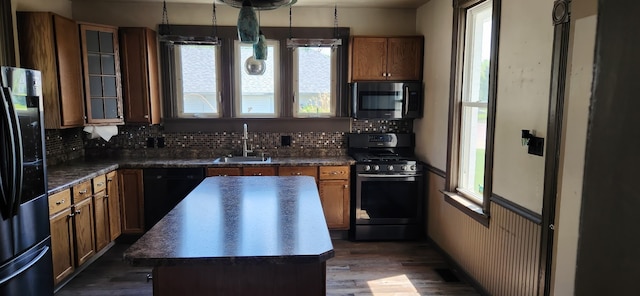 kitchen featuring stainless steel appliances, a sink, a kitchen island, dark wood-style floors, and decorative backsplash