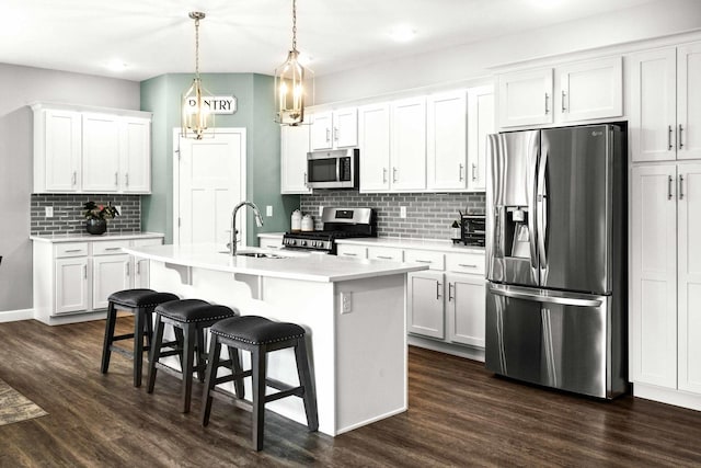 kitchen with appliances with stainless steel finishes, a sink, backsplash, light countertops, and a kitchen bar