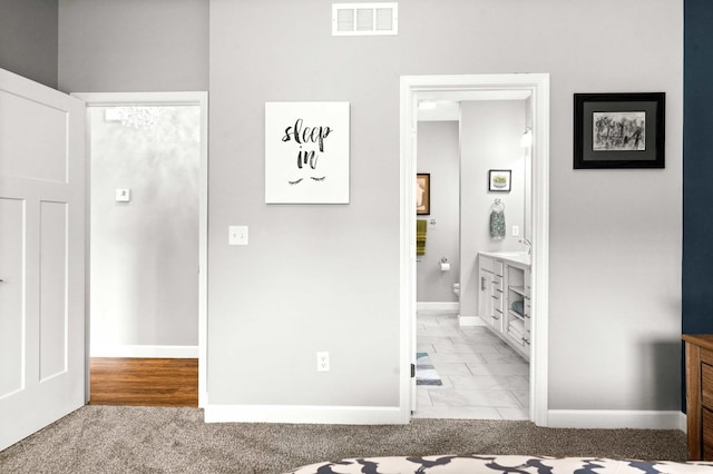 unfurnished bedroom featuring light marble finish floors, baseboards, and connected bathroom