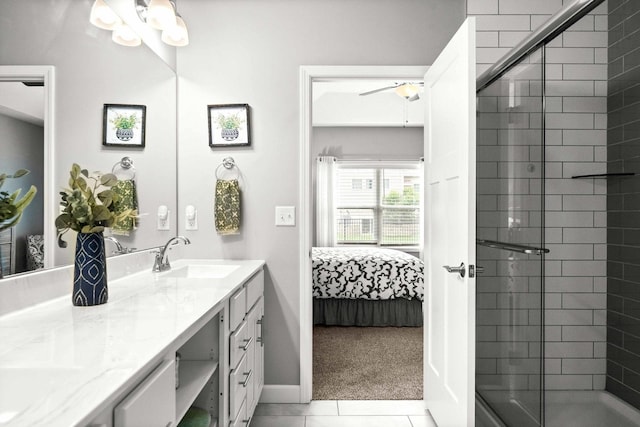 ensuite bathroom with a stall shower, double vanity, a ceiling fan, baseboards, and tile patterned floors