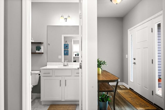 bathroom featuring baseboards, vanity, and toilet