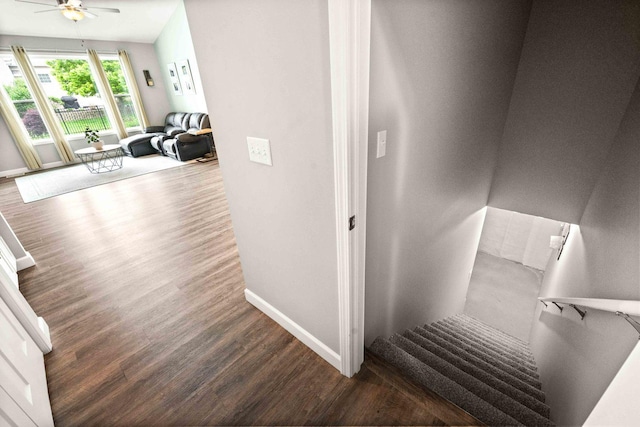 stairs featuring wood finished floors, baseboards, and a ceiling fan