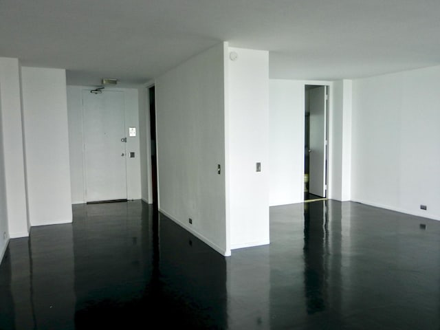 spare room featuring concrete flooring and baseboards