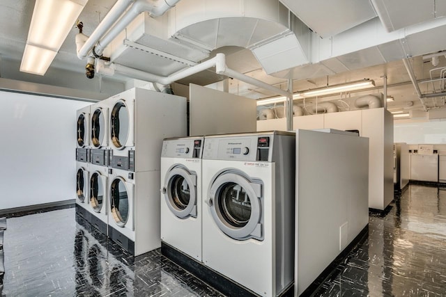 community laundry featuring washer and dryer, stacked washer and clothes dryer, and dark marble finish floors