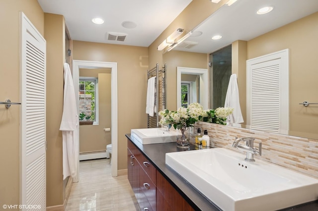505 Jackson Ave, Glencoe, IL 60022 - full bathroom featuring baseboard heating, toilet, decorative backsplash, baseboards, and double vanity