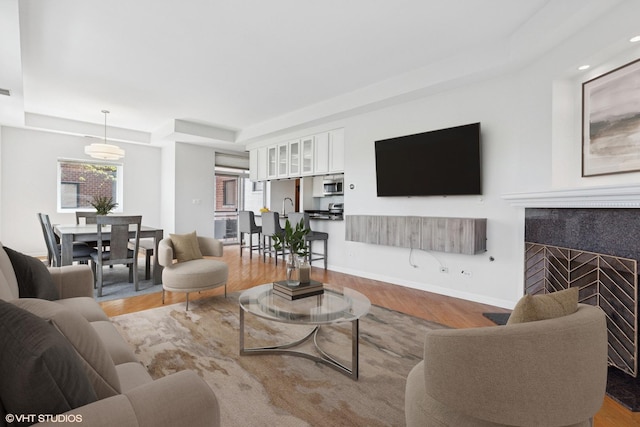 2307 W Wolfram St Unit 415, Chicago, IL 60618 - living room with a tray ceiling, wood finished floors, a tiled fireplace, and baseboards