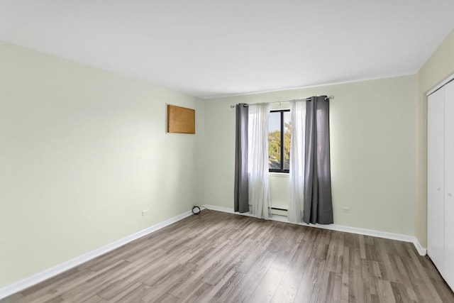 unfurnished room featuring wood finished floors, baseboard heating, and baseboards