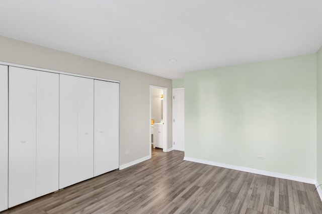 unfurnished bedroom with light wood finished floors, a closet, and baseboards