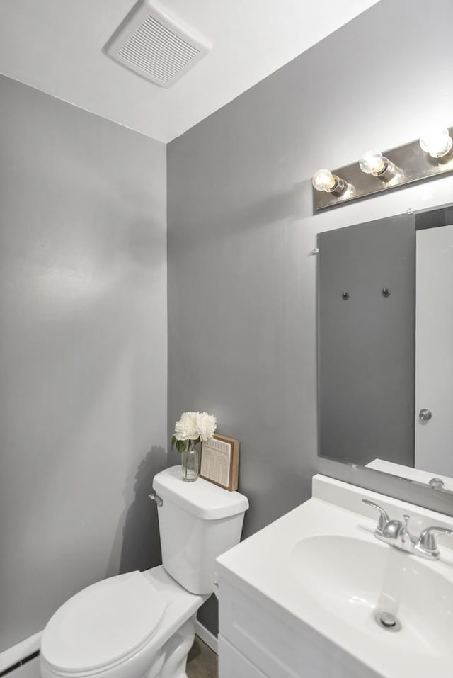 half bathroom featuring toilet, baseboard heating, vanity, and baseboards