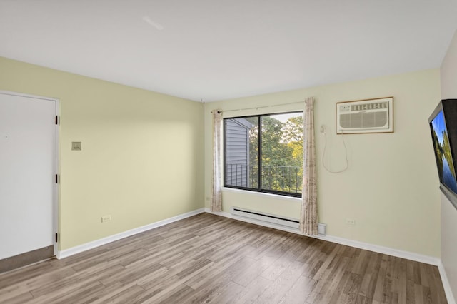 unfurnished room featuring a wall unit AC, wood finished floors, baseboard heating, and baseboards