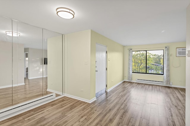 spare room with a baseboard radiator, wood finished floors, and baseboards