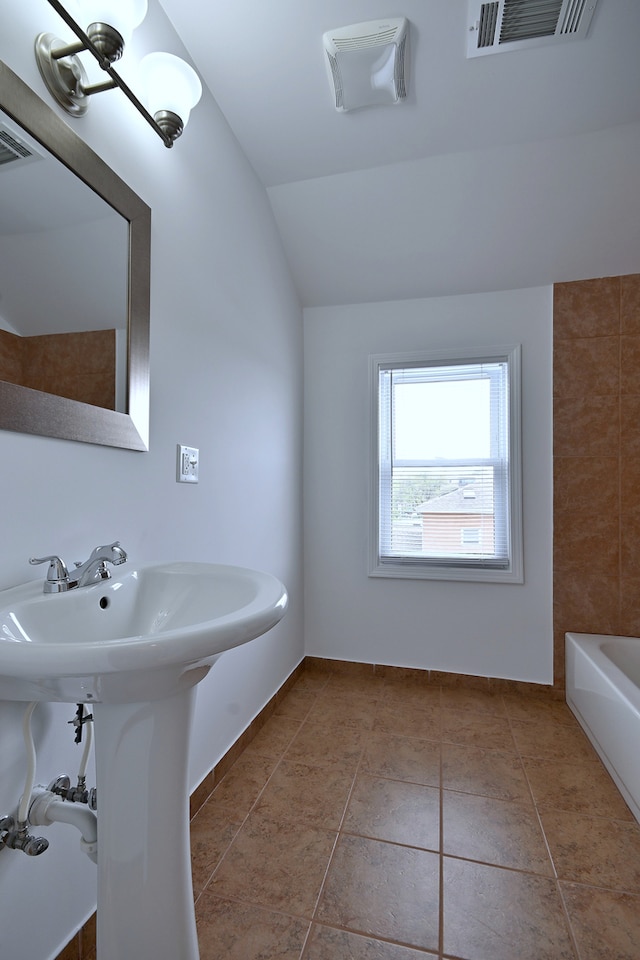 5104 N Austin Ave, Chicago, IL 60630 - bathroom featuring a bath, tile patterned floors, vaulted ceiling, a sink, and baseboards