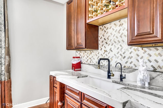 1327 Greenwood Ave, Deerfield, IL 60015 - kitchen featuring a sink, backsplash, light stone counters, glass insert cabinets, and baseboards