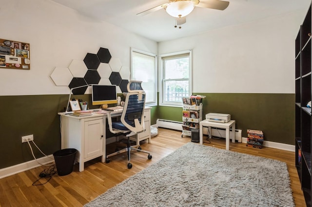 office featuring baseboard heating, a ceiling fan, light wood-style floors, and a baseboard heating unit