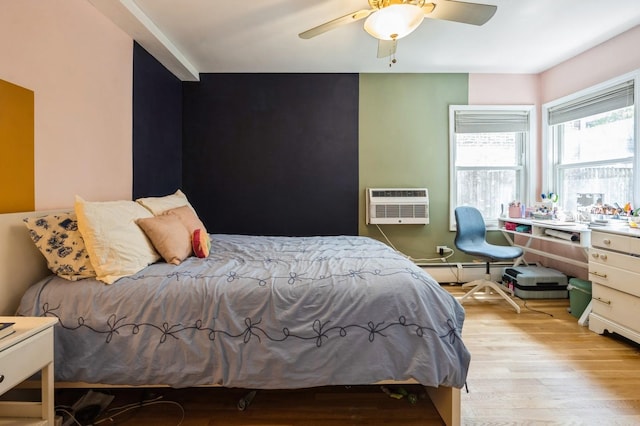 bedroom featuring wood finished floors, a wall mounted AC, a baseboard heating unit, and ceiling fan