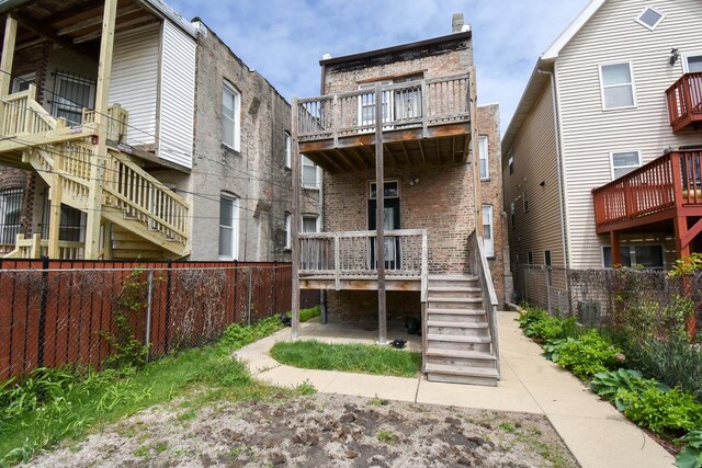 523 E 41st St, Chicago, IL 60653 - rear view of property featuring a fenced backyard, stairs, brick siding, and a wooden deck