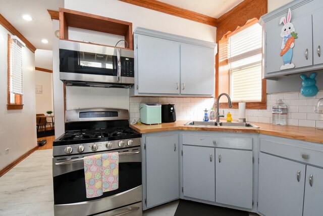 523 E 41st St, Chicago, IL 60653 - kitchen with stainless steel appliances, a sink, tasteful backsplash, ornamental molding, and light wood finished floors