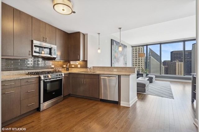 60 E Monroe St Unit 3308, Chicago, IL 60603 - kitchen with stainless steel appliances, decorative backsplash, dark wood-type flooring, a peninsula, and light stone countertops