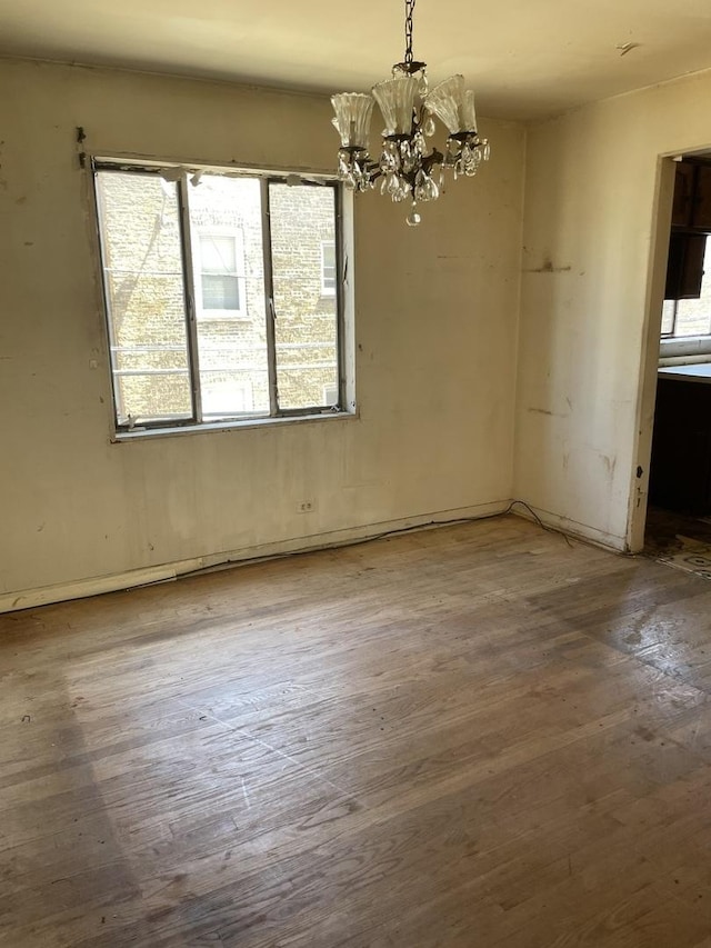 unfurnished dining area with hardwood / wood-style flooring, healthy amount of natural light, and a chandelier