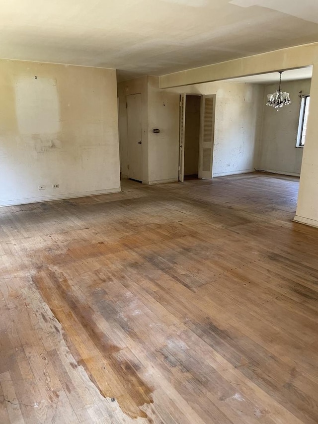 empty room featuring a chandelier and hardwood / wood-style flooring