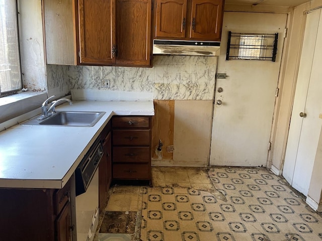 kitchen with under cabinet range hood, dishwasher, a sink, light countertops, and light flooring