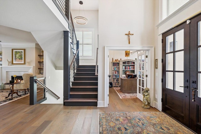 604 Cayman Way, Savoy, IL 61874 - entryway featuring wood-type flooring, stairs, a warm lit fireplace, french doors, and a high ceiling
