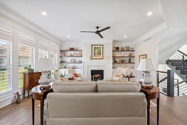 604 Cayman Way, Savoy, IL 61874 - living room with ornamental molding, a ceiling fan, wood finished floors, a lit fireplace, and built in shelves