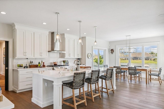 604 Cayman Way, Savoy, IL 61874 - kitchen with wall chimney exhaust hood, plenty of natural light, dark wood-style floors, a center island with sink, and recessed lighting
