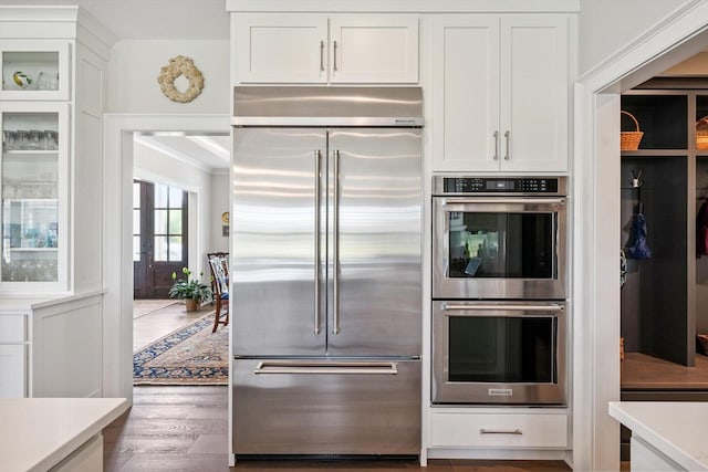 604 Cayman Way, Savoy, IL 61874 - kitchen featuring appliances with stainless steel finishes, white cabinetry, light countertops, glass insert cabinets, and wood finished floors