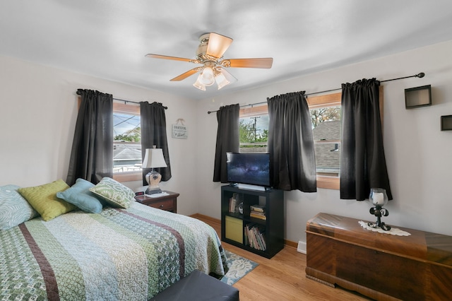 bedroom with multiple windows, wood finished floors, ceiling fan, and baseboards