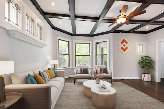 living area with coffered ceiling, wood finished floors, baseboards, beamed ceiling, and a ceiling fan