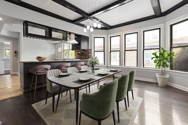 dining area featuring baseboards, healthy amount of natural light, wood-type flooring, coffered ceiling, and beamed ceiling
