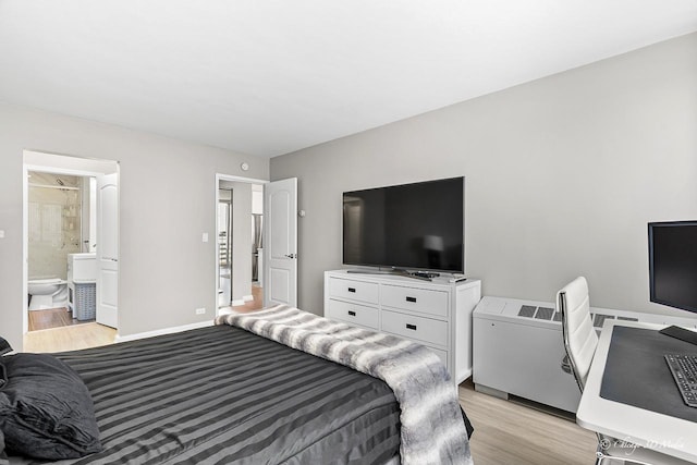 bedroom with light wood-type flooring, baseboards, and connected bathroom
